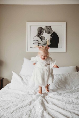 A little girl jumps on a white bed