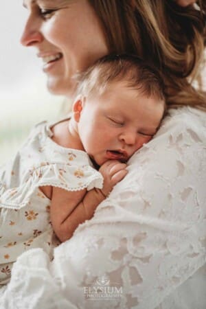 A baby girl lays on her mamma's shoulder sleeping