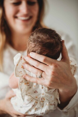 A mother's hands hold her baby girl's head