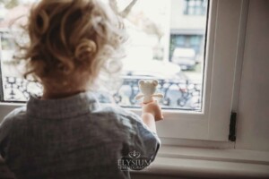 Newborn Photography: a little boy shows his teddy bear out the window