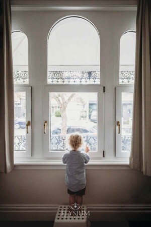 Newborn Photography: a little boy holds his teddy bear up to a window