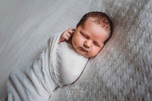 Newborn Photography: a baby boy lays wrapped on a white blanket