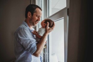 Newborn Photography: a father smiles as he gazes at his baby boy