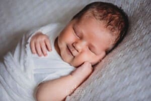 Newborn Photography: a baby boy lays wrapped on a white blanket