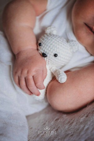 Newborn Photography: a baby's tiny fingers hold a small teddy bear