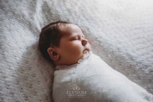 Newborn Photography: a baby boy lays wrapped on a white blanket