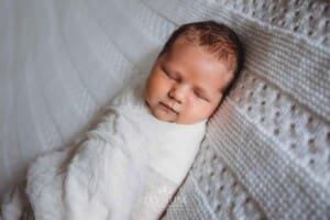 Newborn Photography: a baby boy lays wrapped on a white blanket