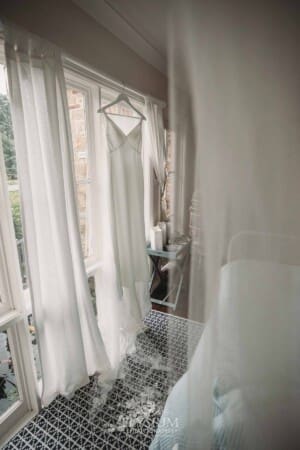Sydney Wedding - a brides dress hangs from a window in a bright room