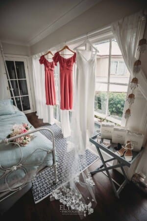 Sydney Wedding - a bridal gown hangs with the bridesmaid dresses in a window