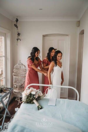 Sydney Wedding - a bridesmaid does up the back of the bridal gown