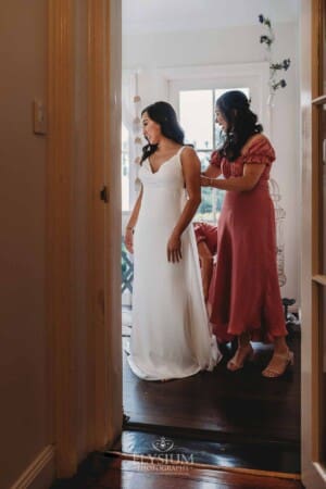 Sydney Wedding - a bridesmaid does up the back of the bridal gown