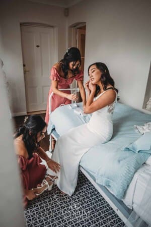 Sydney Wedding - a bride puts on earrings as bridesmaids fasten her shoes