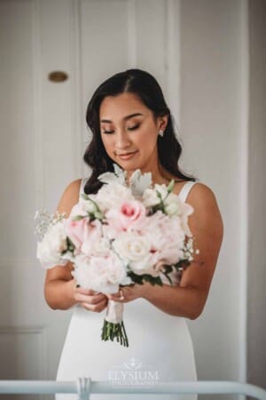 Sydney Wedding - a bride fastens a pendant to her bouquet of flowers