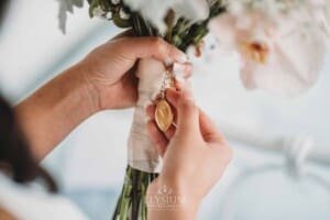 Sydney Wedding - a bride fastens a pendant to her bouquet of flowers