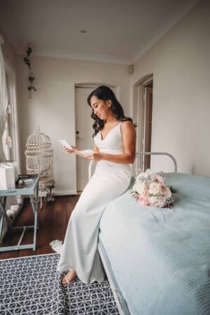 Sydney Wedding - a bride sits on a bed to read a letter from her groom