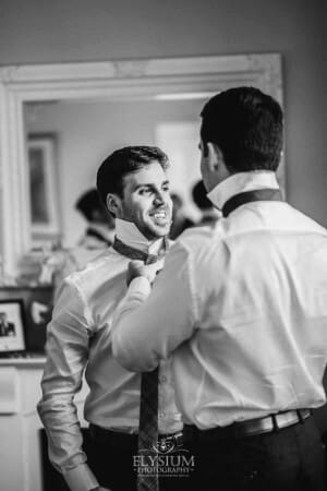 Sydney Wedding - a groomsman helps the groom with his tie