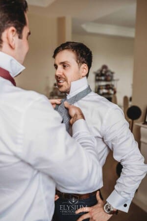 Sydney Wedding - a groomsman helps the groom with his tie