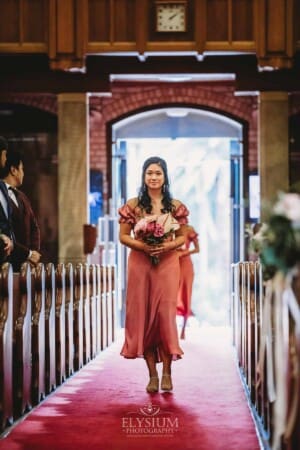 Sydney Wedding - a bridesmaid walks down a church aisle to the ceremony