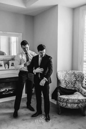 Sydney Wedding - a groomsman helps the groom with his suit jacket
