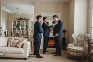 Sydney Wedding - the groom helps his groomsmen with their suit jackets