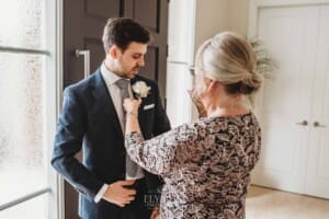 Sydney Wedding - a woman pins the flowers onto the groom's jacket