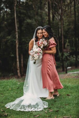 Sydney Wedding - a bride hugs her bridesmaid in the gardens at Springfield House