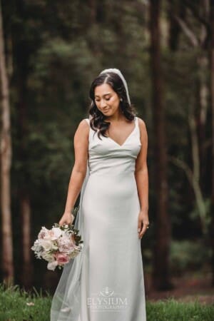 Sydney Wedding - a bride stands in the gardens at Springfield House admiring her bouquet