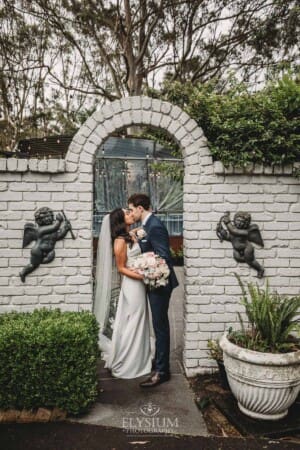 Sydney Wedding - bride and groom kiss beneath an arch at Springfield House