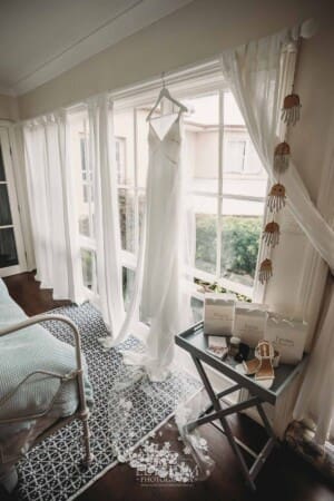 Sydney Wedding - a brides dress hanging in a bright window