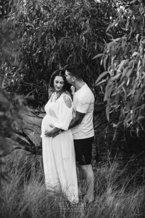 Outdoor Session - a man kisses his pregnant wife on the head