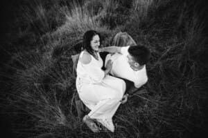 Outdoor Session - an expectant couple lay on a blanket in long grass