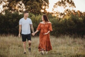 Outdoor Session - a couple walk through long grass at sunset