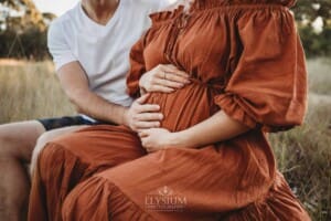 Outdoor Session - a man places his hand on his pregnant wife's belly