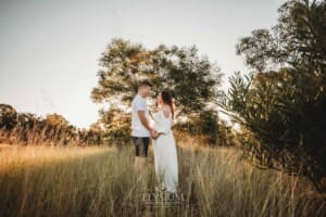 Outdoor Session - a couple hold hands standing in front of trees at sunset