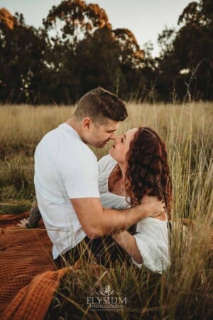 Outdoor Session - a couple sit in long grass and press their noses together