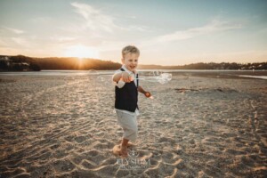 A child plays with bubbles on a sandy beach at sunset
