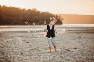 A child plays on the beach sand with bubbles at sunset
