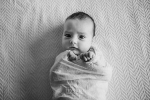 A newborn baby lays wrapped on a white blanket