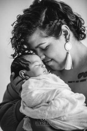 A mother nuzzles her nose into her newborn baby's cheek