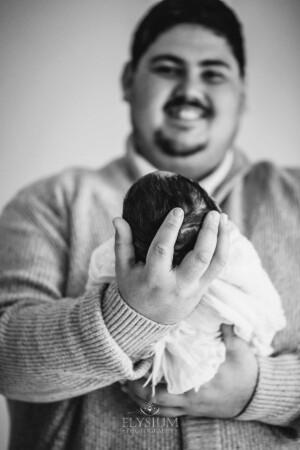A fathers hands holding his tiny baby girls head, black and white photograph