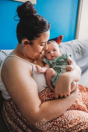 A mother holds her newborn baby boy in her arms as they sit in a chair