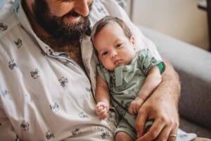 A father sits in a chair and holds his baby girl in his arms