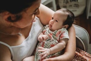 A mother cuddles her newborn baby girl in her arms as she pokes out her tongue