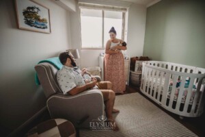 Parents hold their twin babies as they stand in the nursery