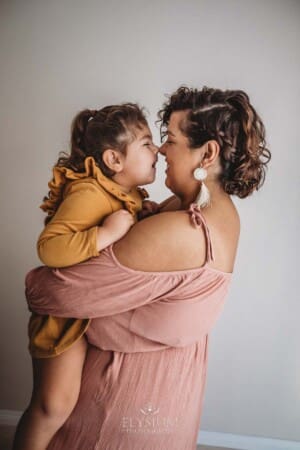 A little girl and her mother rub their noses together and giggle