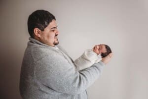 A father holds his tiny newborn baby girl in his hands and smiles