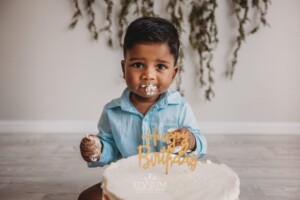 A baby boy plays with icing during his messy cake smash session
