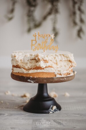 A cake with pieces missing after being smashed by a baby