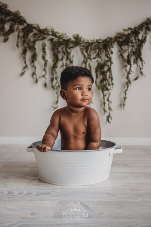 A baby washes off in a bubble bath after his messy cake smash session