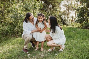 Parents tickle their little girl as she giggles at sunset